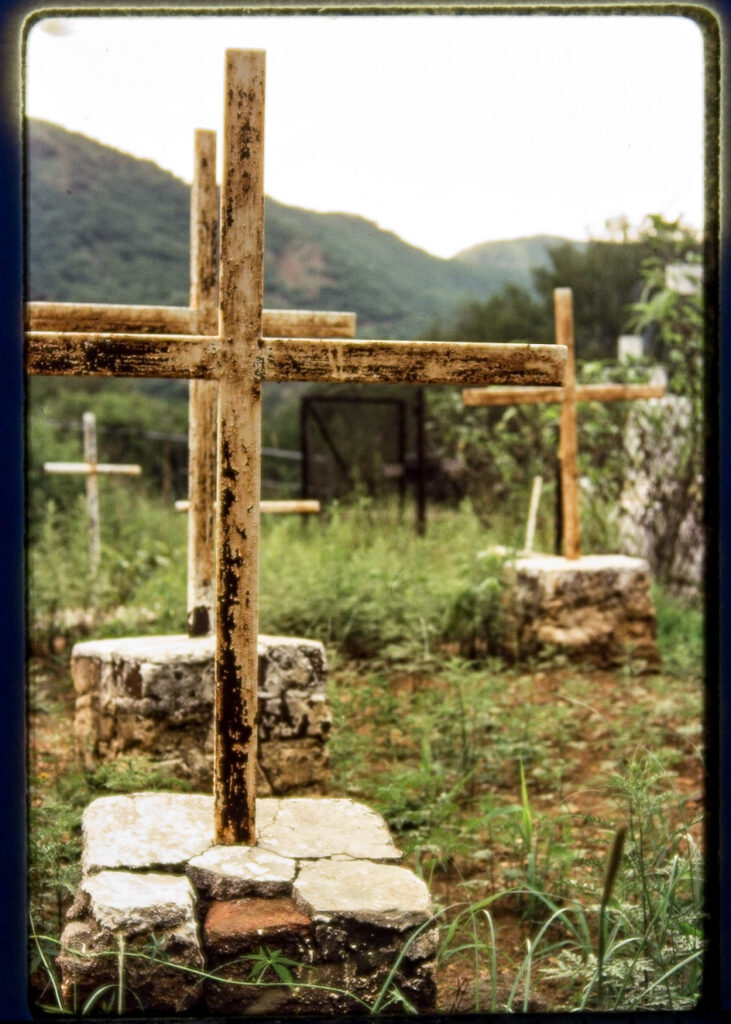 colour photo of grave markers with green hills in background