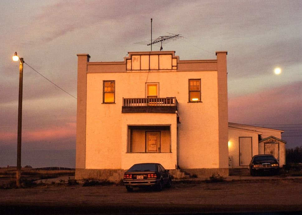 colour photo of building in late afternoon sunlight with moon in sky