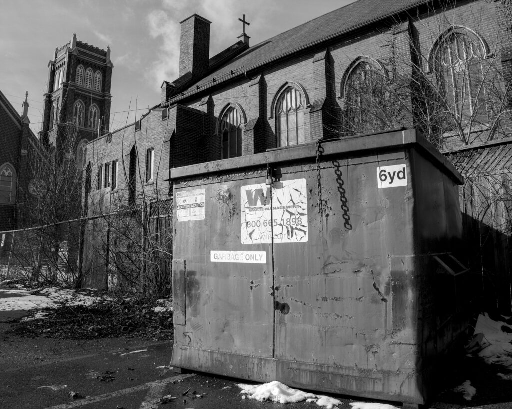 black and white photo of a large waste bin with two churches in background
