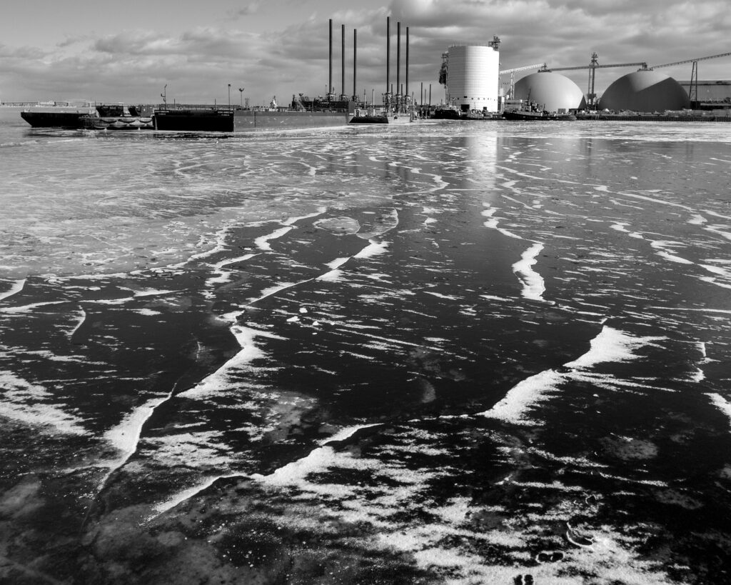 black and white photo of frozen harbour with industrial structures in background