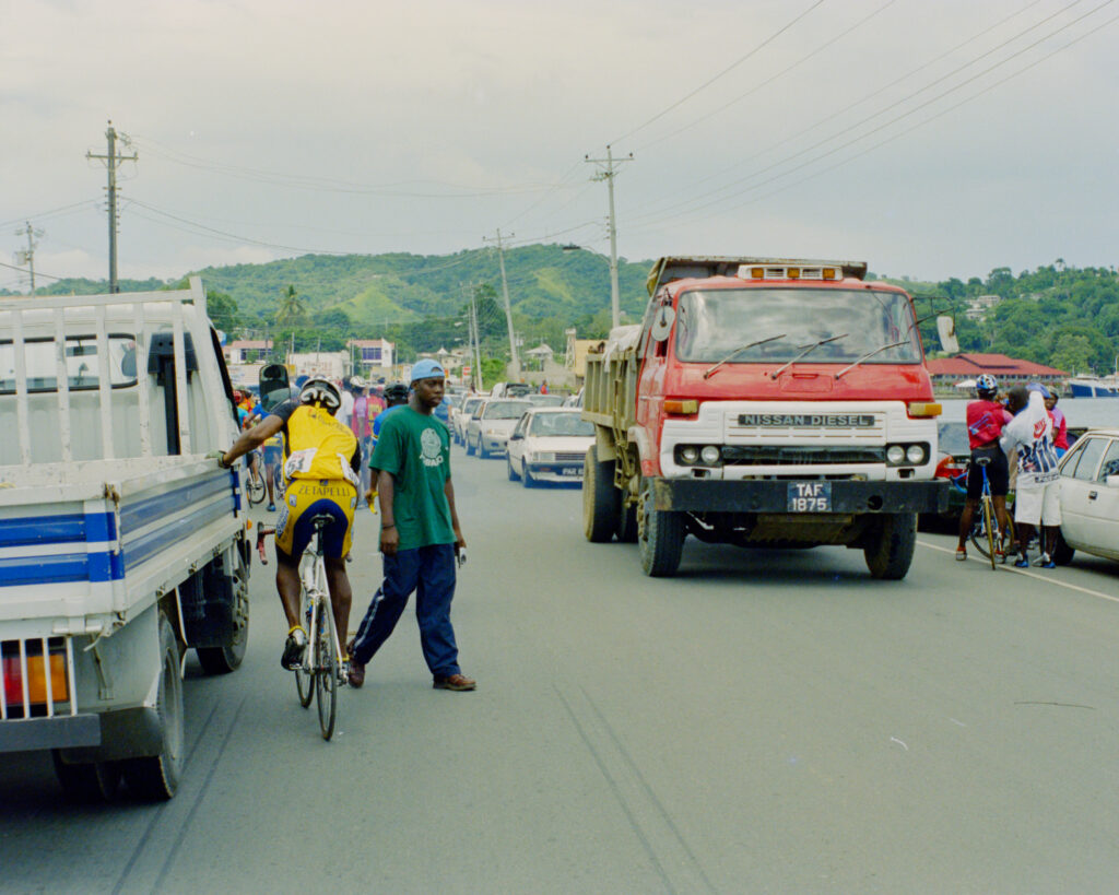 colour photo of vehicle traffic on crowded street with green hills in background