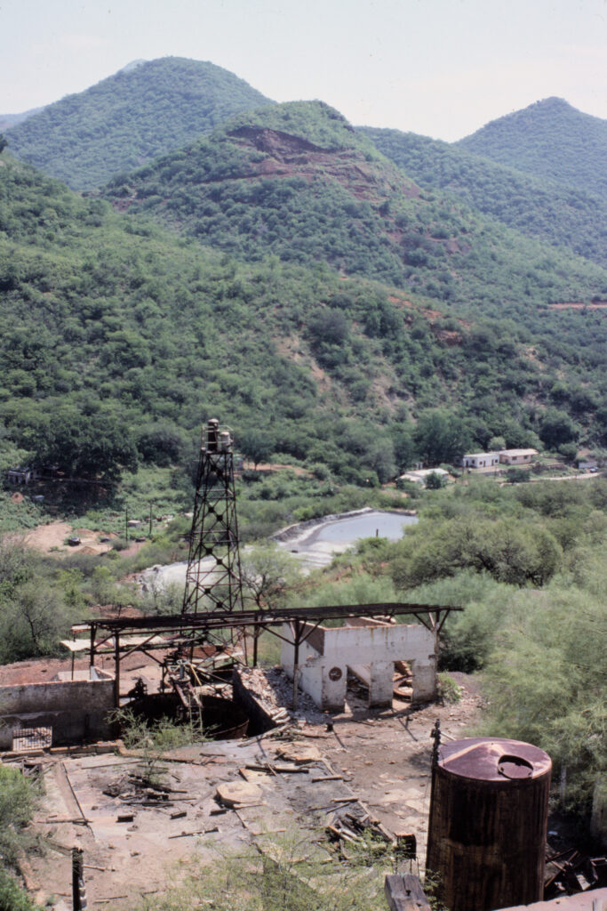 colour photo looking down at abandoned mine site. Green mountains in background