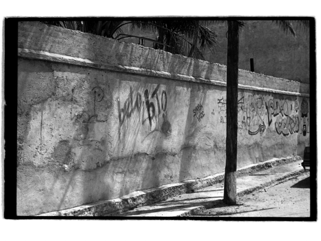 Black and white photo of shadows and graffiti on masonty wall