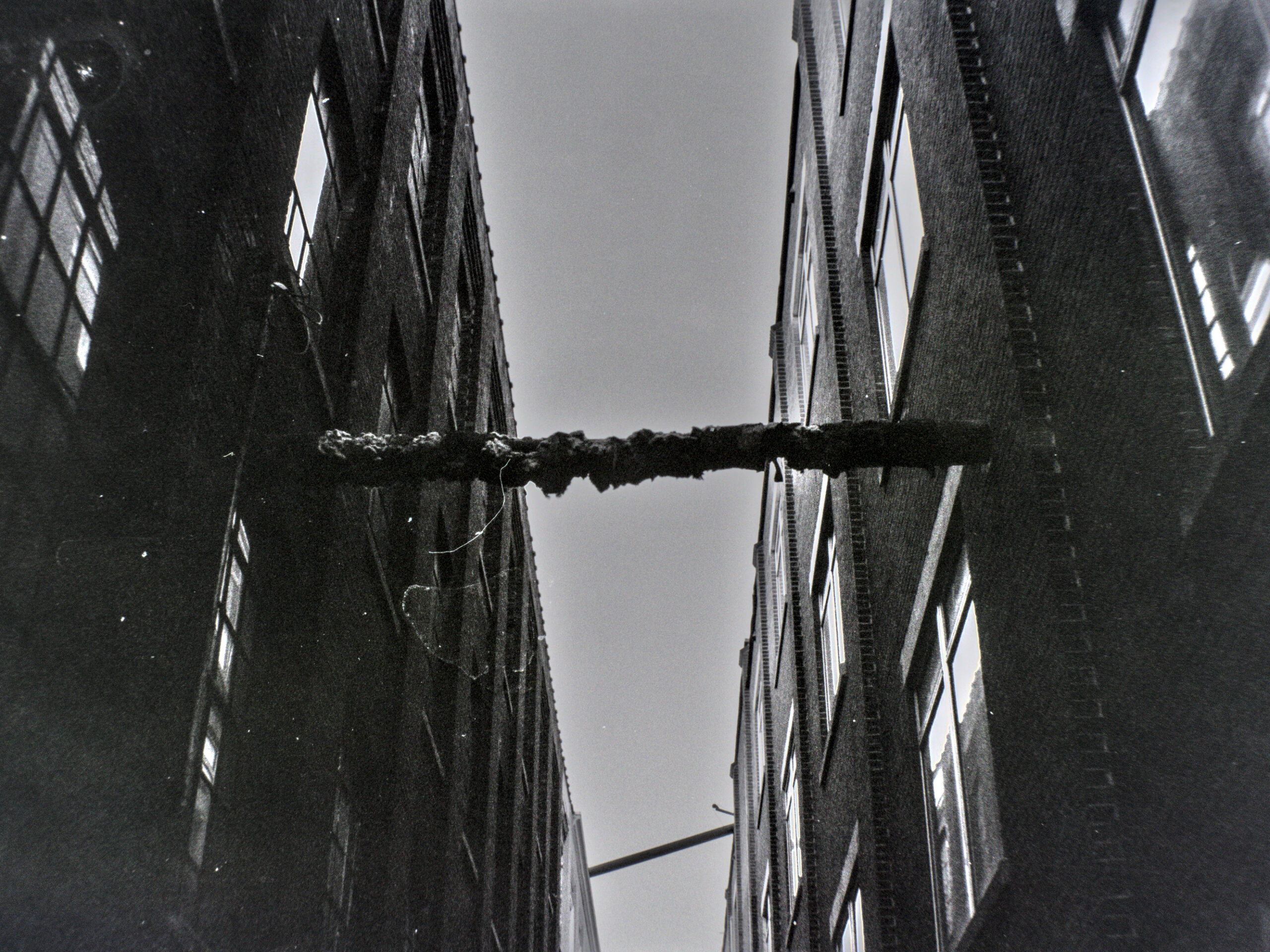black and white photo looking up at the sky between two old brick buildings.