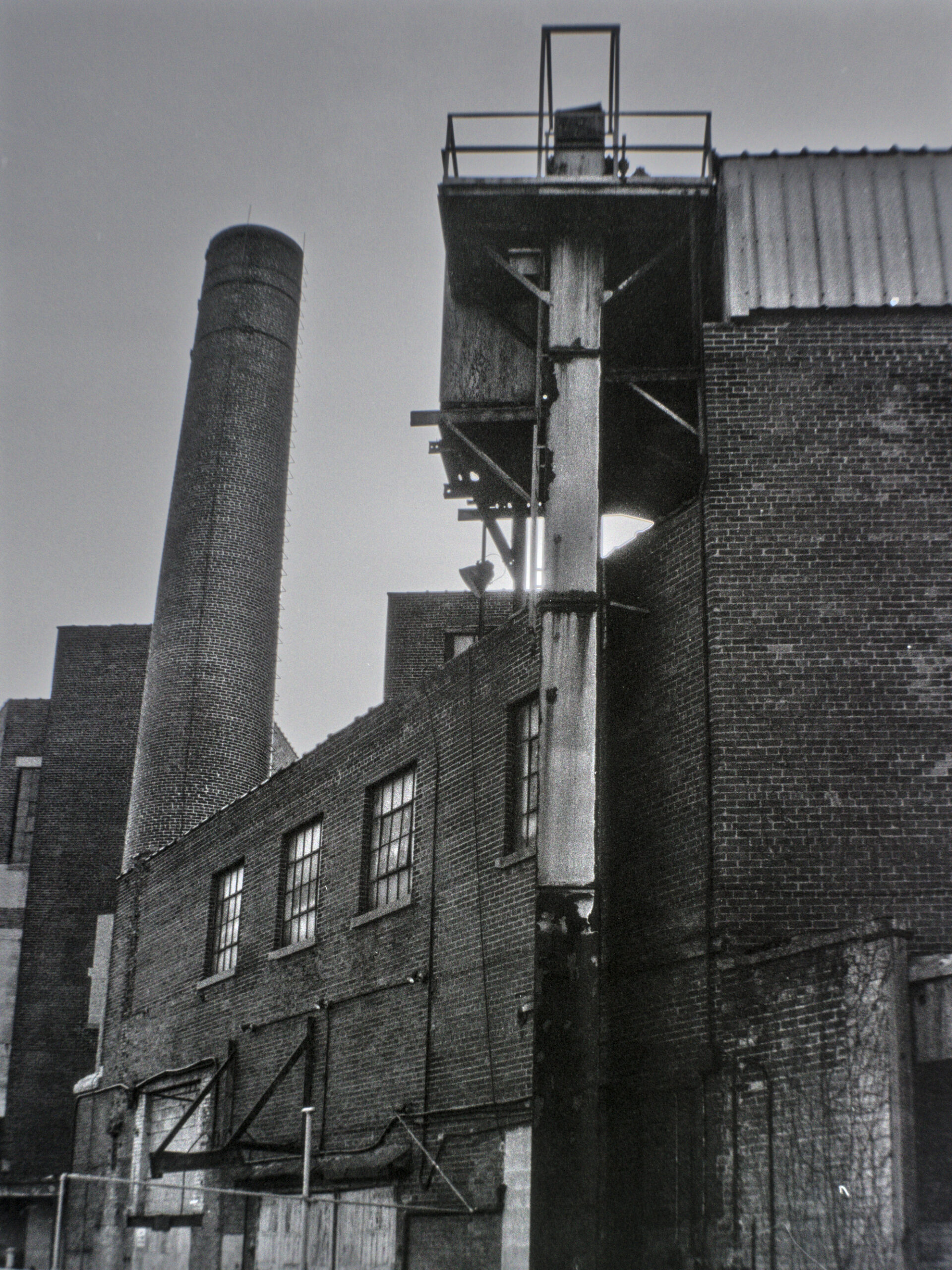 black and white photo of old industrial brick building and smokestack