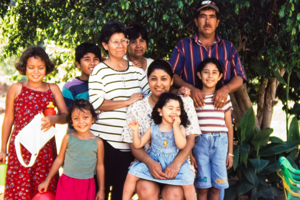 Colour photo of 9 people outdoors posing and smiling for the camera