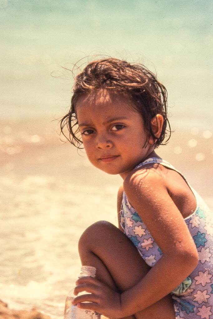 Colour photo of small girl at in sunlight at the beach